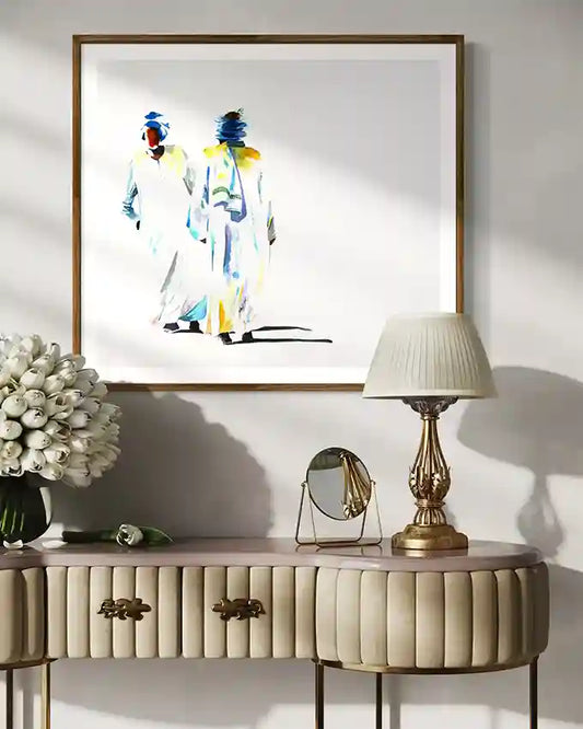 Decorative console table with a lamp, mirror, and flowers against a wall with framed art print by artist "Galal Yousif", UAE