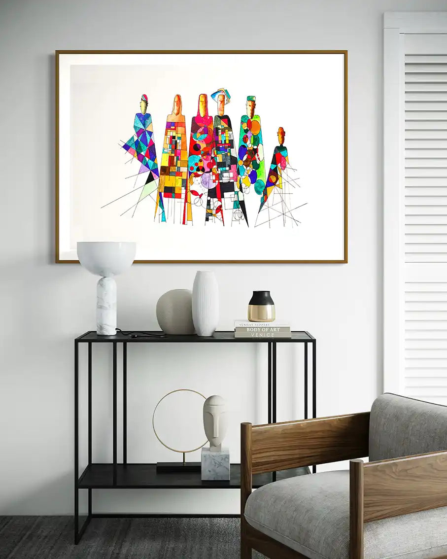 'Community Influences' art print by artist Yousif Ibrahim on a wall above a black console table with decorative items. UAE