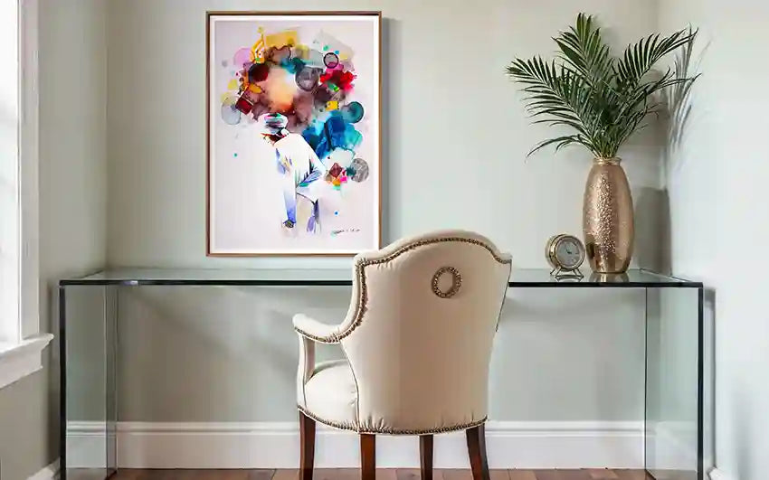 Glass desk with a chair, decorative plant, and framed art artist print by Galal Yousif on a light gray wall. in UAE