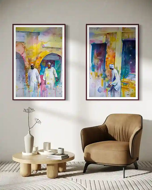 Two colorful abstract paintings on a wall above a beige armchair and coffee table.