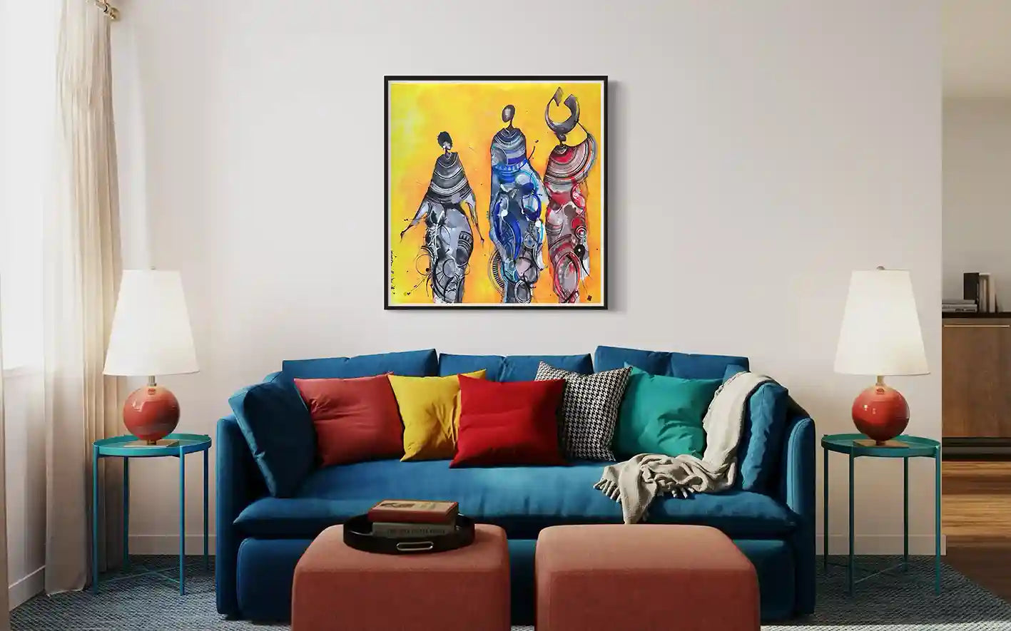 Sun-Kissed by Mohamed Wraag in black frame above teal sofa, three Sudanese women in traditional dress on golden canvas art