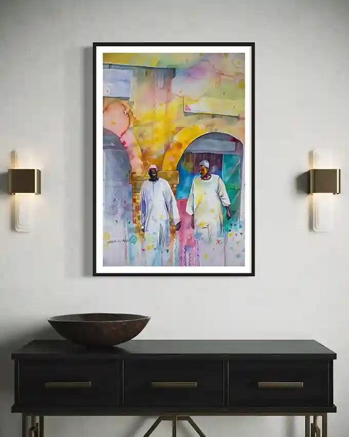 Framed art print by Artist Galal Yousif of two people walking, mounted on a wall above a black console table. in UAE