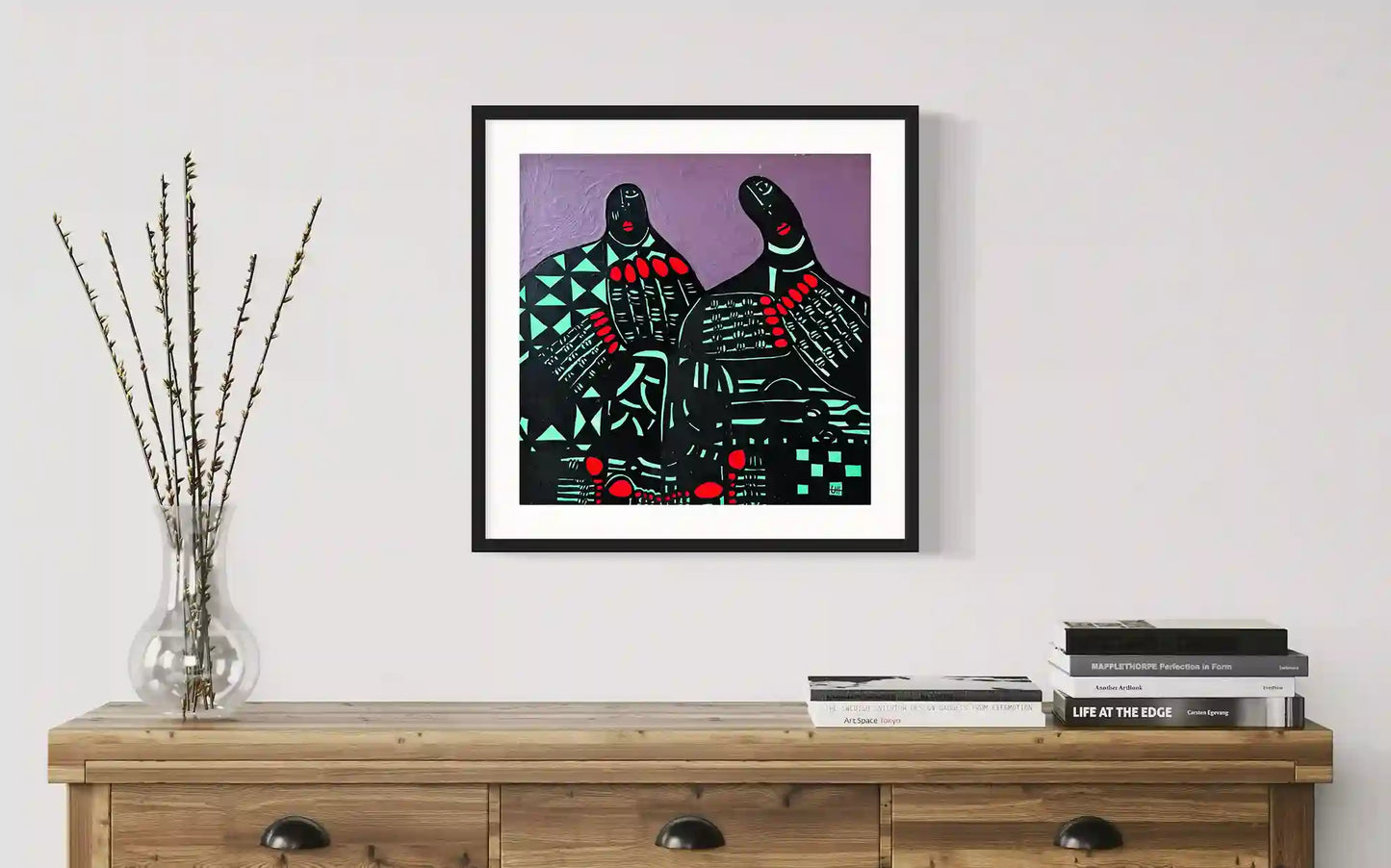 A Double Soul by Usra Hamza in black frame on wall above wooden console with stacked books and glass vase with dried stems