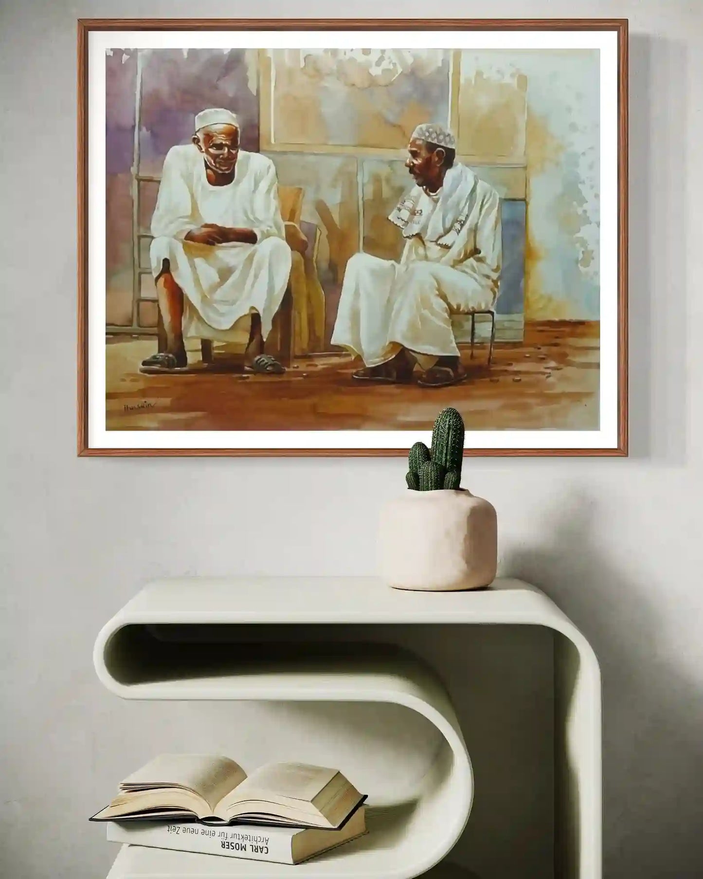 Between Old Friends framed watercolor by Hussein Merghani above white console with cactus plant home decor mockup