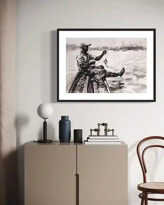 Framed ‘Fisherman at the Nile’ art print displayed on beige sideboard with modern decor including lamp, vase, and wooden chair.