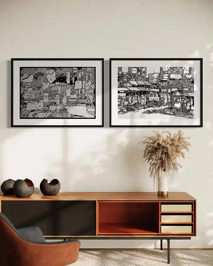 Two framed Osman Gouma black and white art prints displayed above mid-century modern sideboard with decorative pottery and pampas