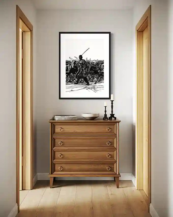 Black and white cattle herder art print by Obada Gabir displayed above wooden chest of drawers in modern hallway interior