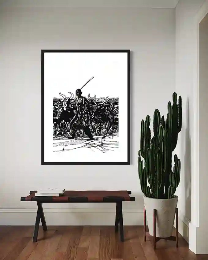 Black and white cattle herder art print by Obada Gabir displayed above wooden bench with large cactus plant in modern room