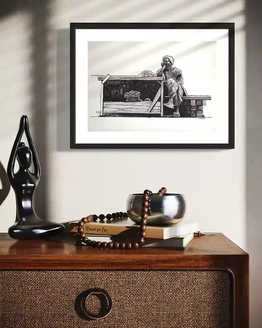 Framed Vegetables Seller ink artwork by Obada Gabir displayed on wall above wooden console with decorative objects