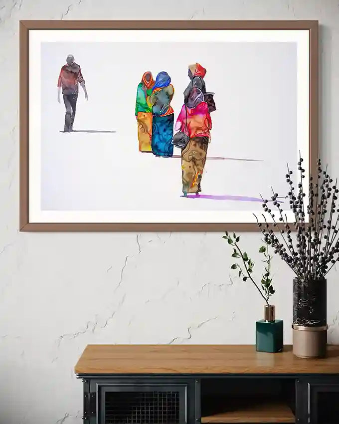 Framed artwork of colorful figures on a wall above a wooden shelf with decorative items.