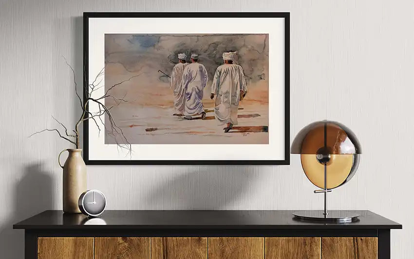 Walking on Air watercolor art print mockup by Salih Abdo showing framed desert scene with three men in modern interior