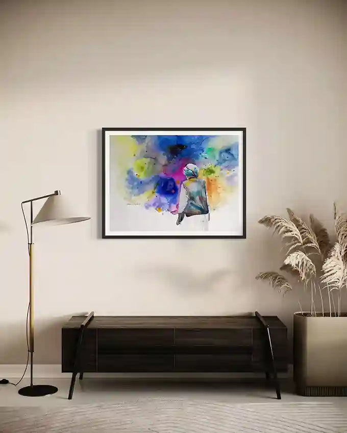 Colorful abstract Art print By Artist Galal Yousif on a wall above a wooden console table in a room with a lamp and plant size 100x75 cm. UAE