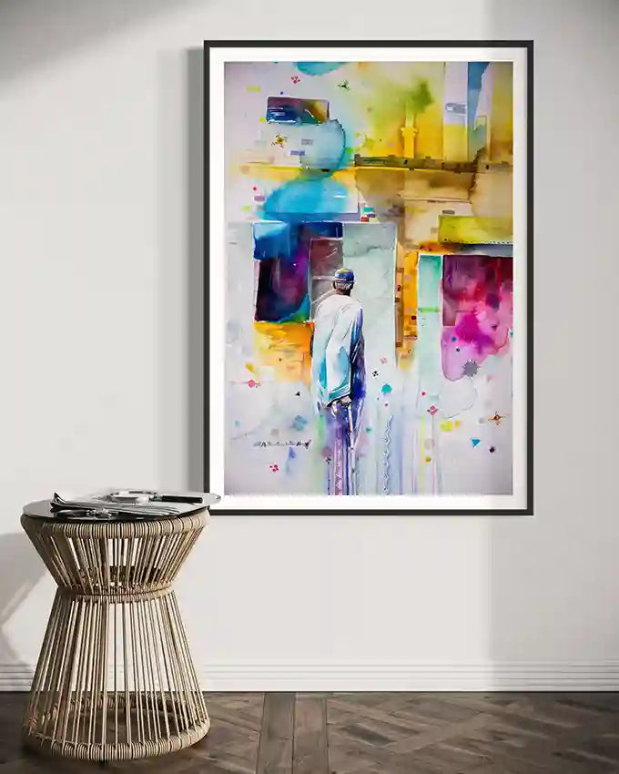 Framed colorful abstract art print of Sudanese man by artist Galal Yousif on a wall above a wicker side table. in UAE