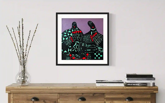 A Double Soul by Usra Hamza in black frame on wall above wooden console with stacked books and glass vase with dried stems