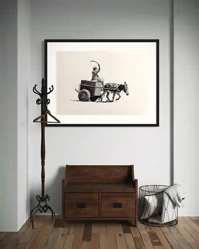 Echoes of the road art print by Obada Gabir in black frame displayed above wooden bench with coat rack and laundry basket in minimalist entryway