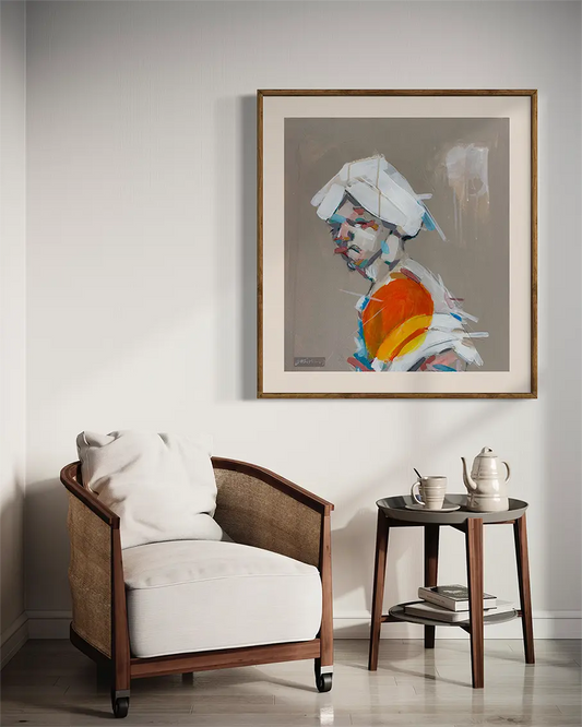 Portrait in White Turban art print by Hazim Alhussain displayed in gold frame above modern chair in elegant living room

