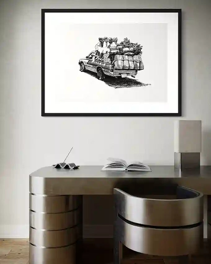 The Long Road art print by Obada Gabir in black frame above modern curved desk with open book and lamp
